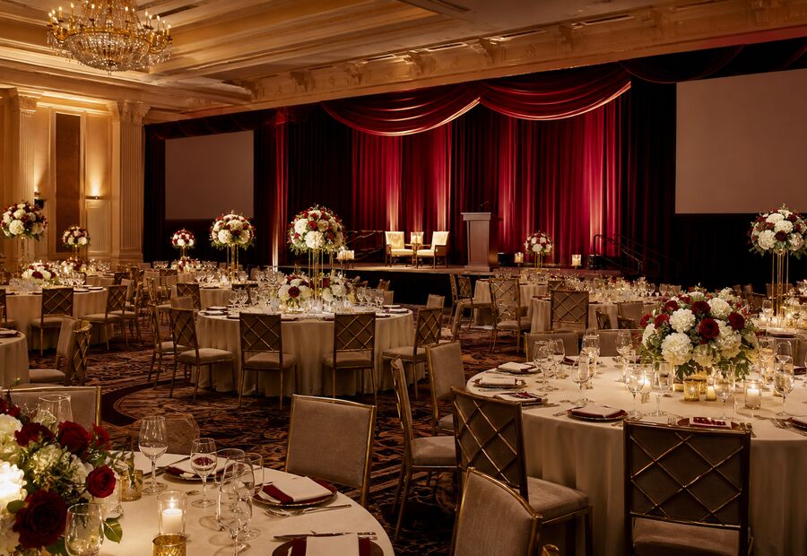 A ballroom laid for a formal dinner under warm lighting
