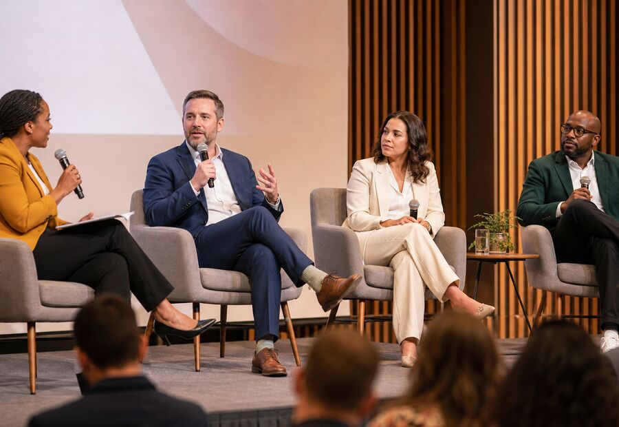 Four panellists on stage in armchairs with an audience